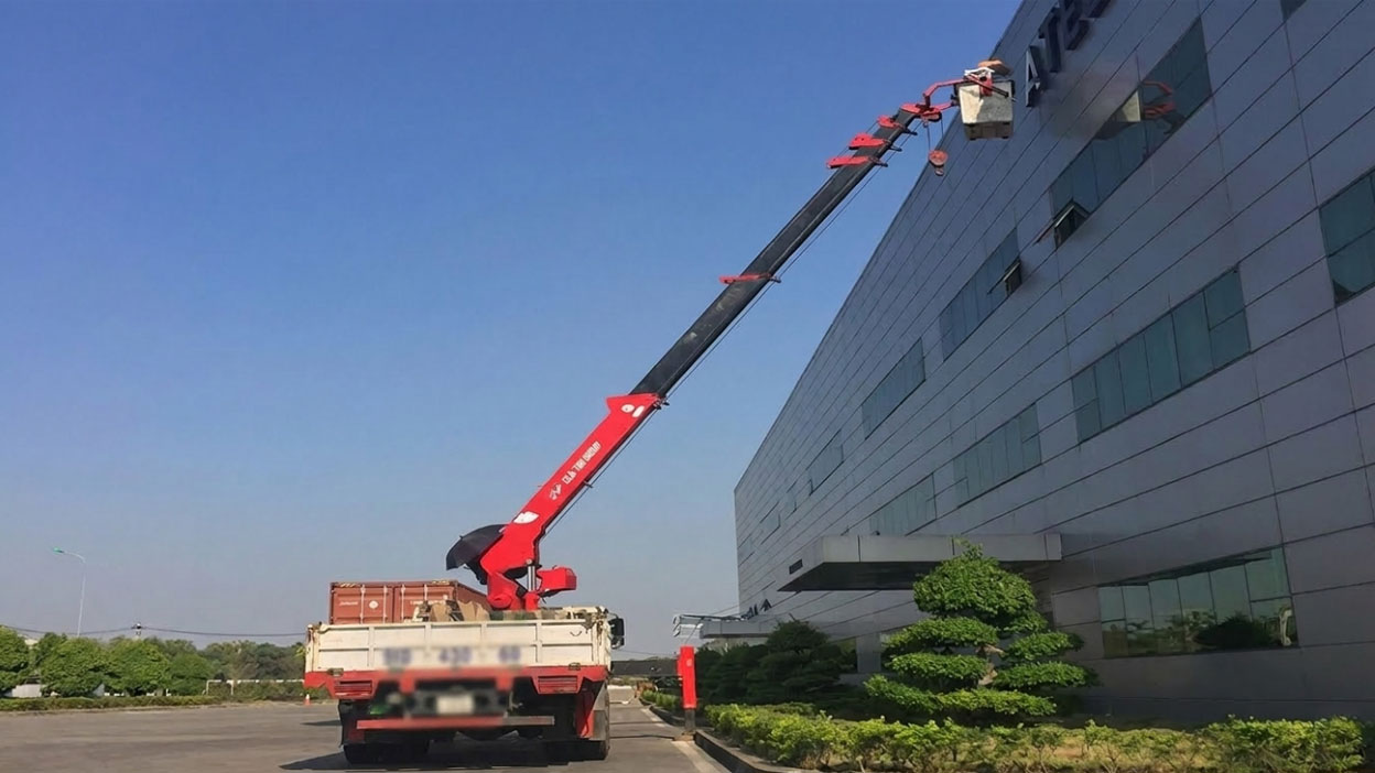 Dùng xe cẩu nâng người lên cao để tu bổ mặt ngoài tòa nhà